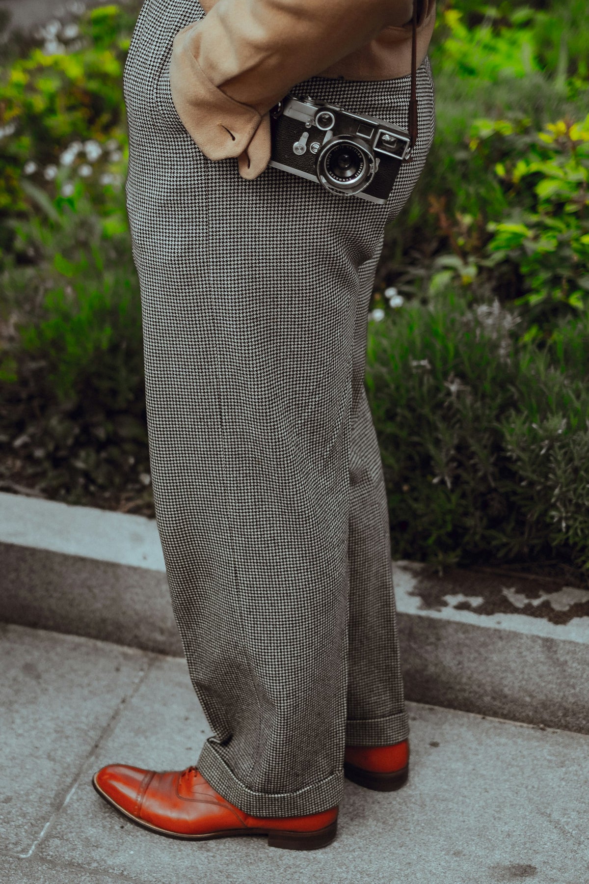Pantalón de lana gris de pierna recta, con zapatos de piel café, sobre una banqueta.