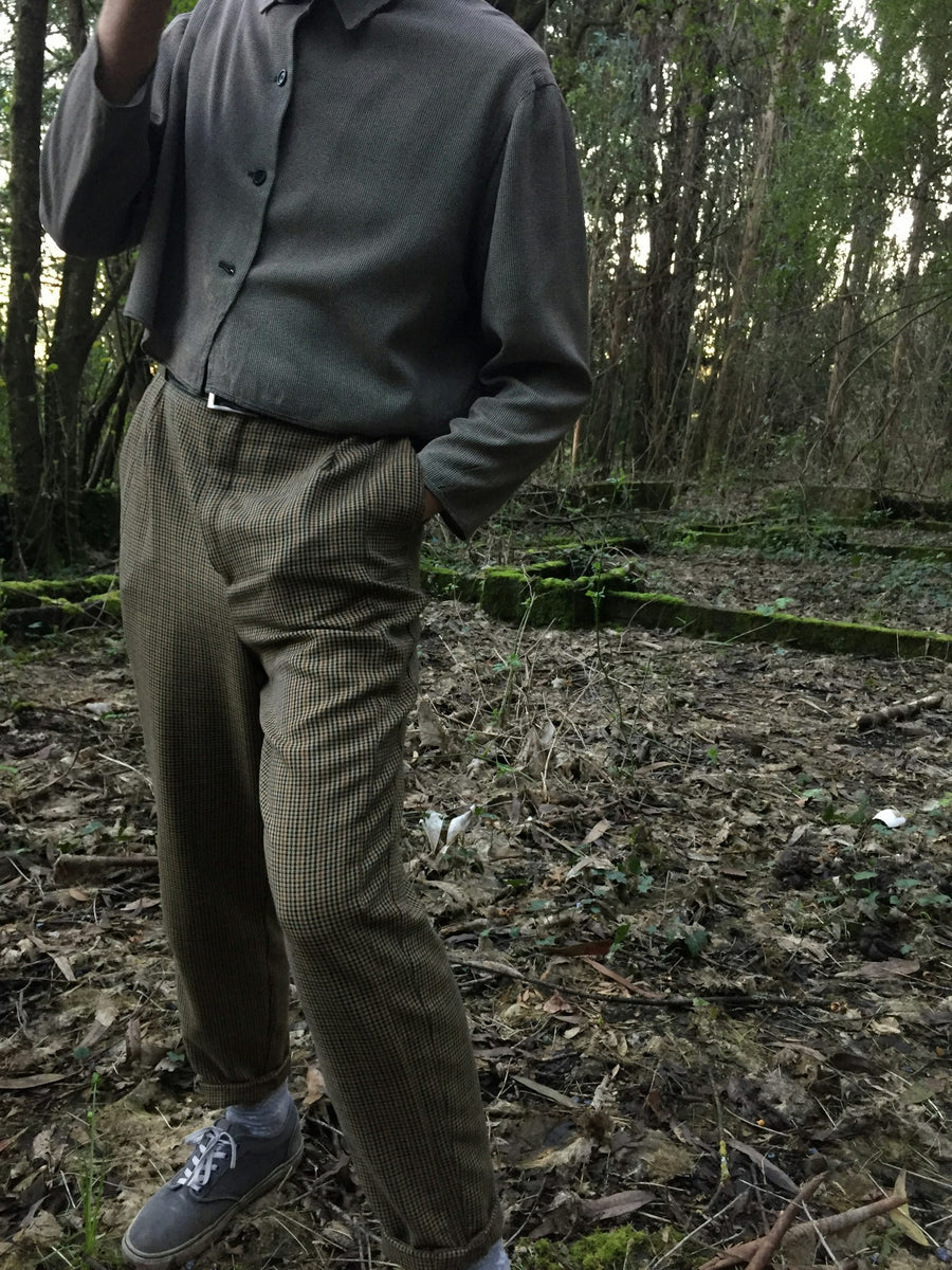 Pantalón de lana fría color olivo, de pinzas, con una camisa gris fajada.