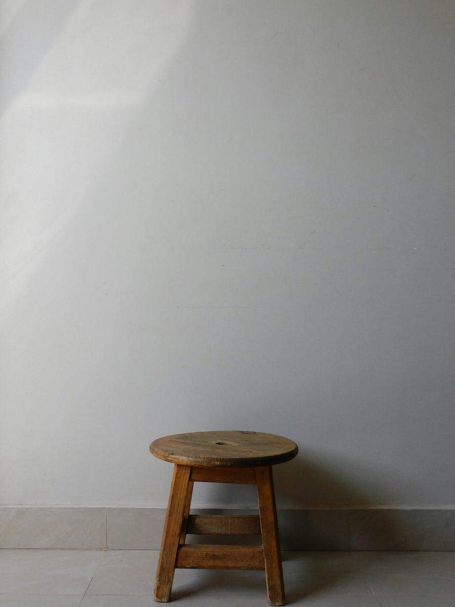 Banco bajo de madera junto a un muro blanco.