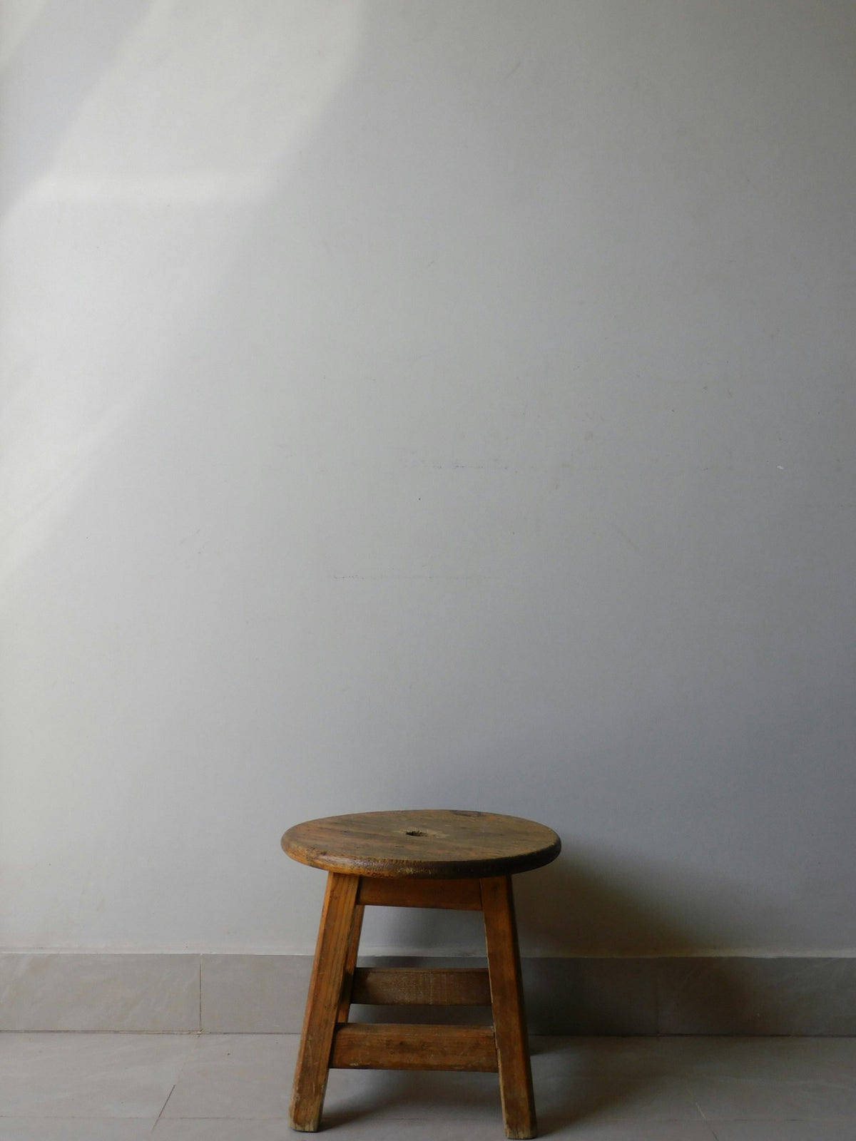 Banco bajo de madera junto a un muro blanco.