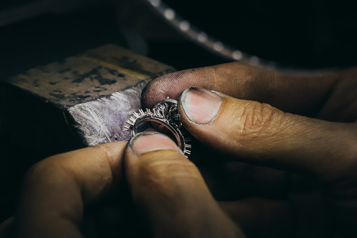Manos de platero pulen un anillo de plata sobre el banco de trabajo.