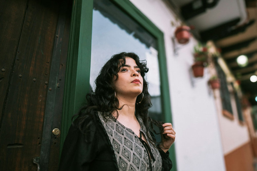 Mariana Pech, de pelo negro y rizado, recargada en el marco verde de una puerta de su taller.