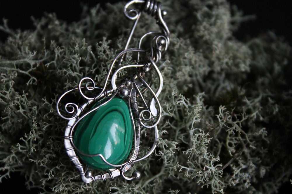 Dije de plata calada con una malaquita verde, colgado de una cadena fina.