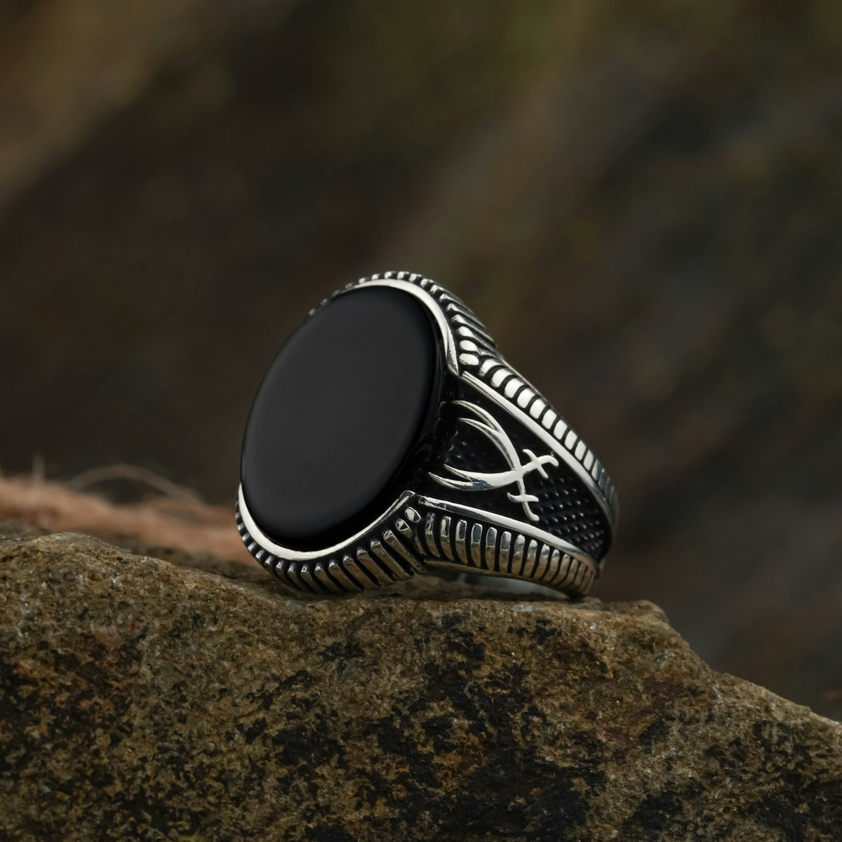 Anillo de sello de plata con una piedra de ónix, sobre una roca.