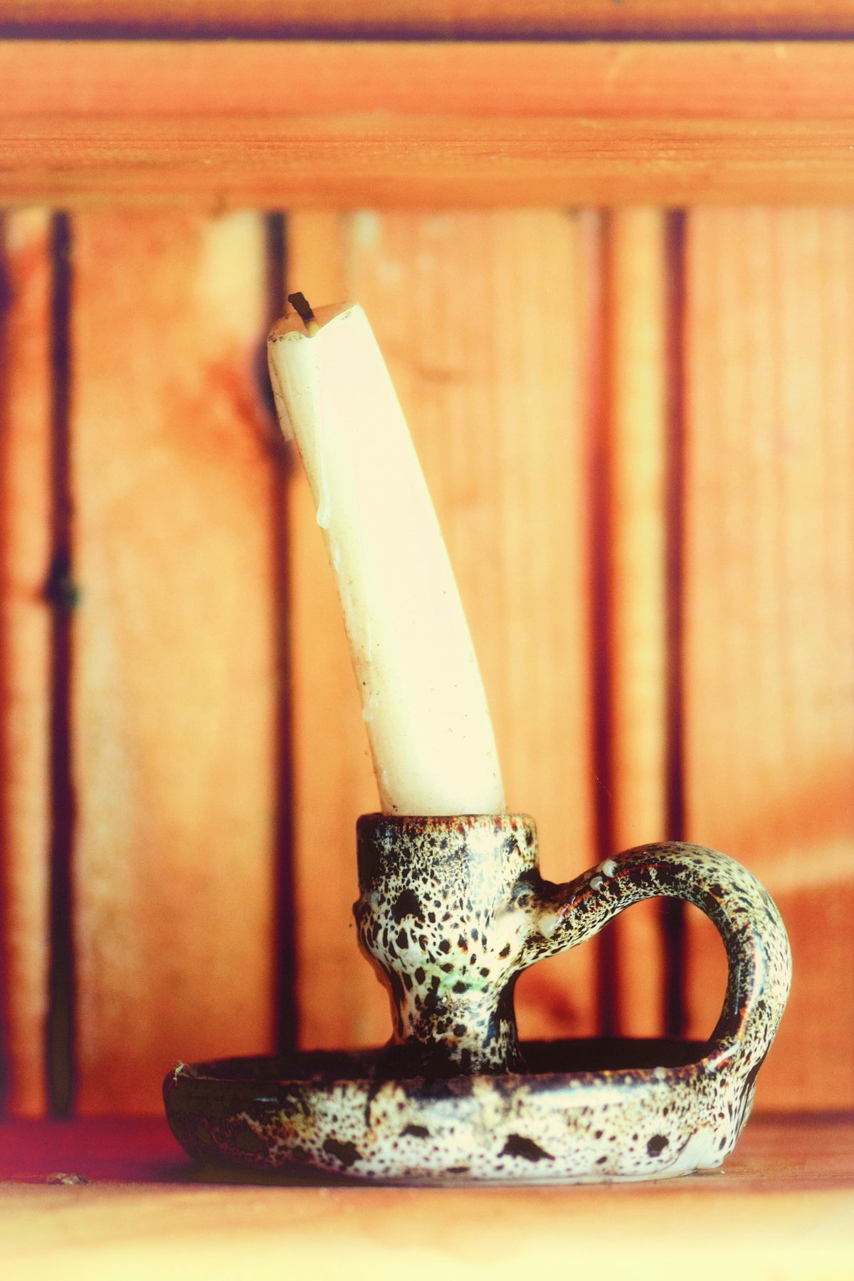 Vela a medio consumir en un candelero de barro moteado.