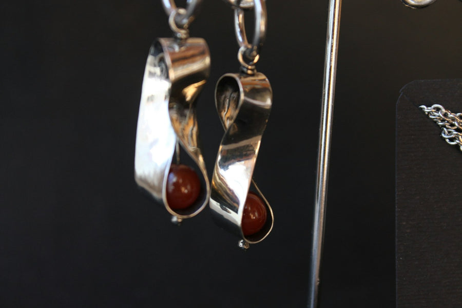 Aretes de plata torcida como un listón, cada uno con una cuenta roja de jaspe.